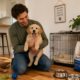 New puppy checklist - owner holding puppy at home surrounded by supplies